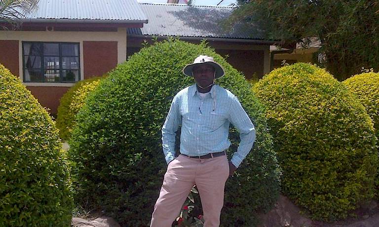 Founder Joseph Nganga standing in front of bushes in Africa.